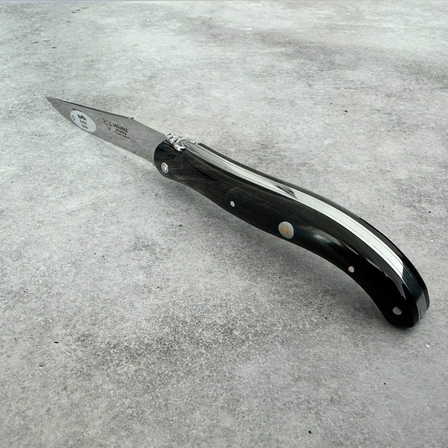 Angled view highlighting the polished buffalo-horn handle and decorative pins of the Laguiole en Aubrac folding knife.