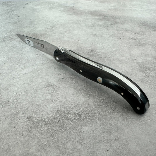 Angled view highlighting the polished buffalo-horn handle and decorative pins of the Laguiole en Aubrac folding knife.