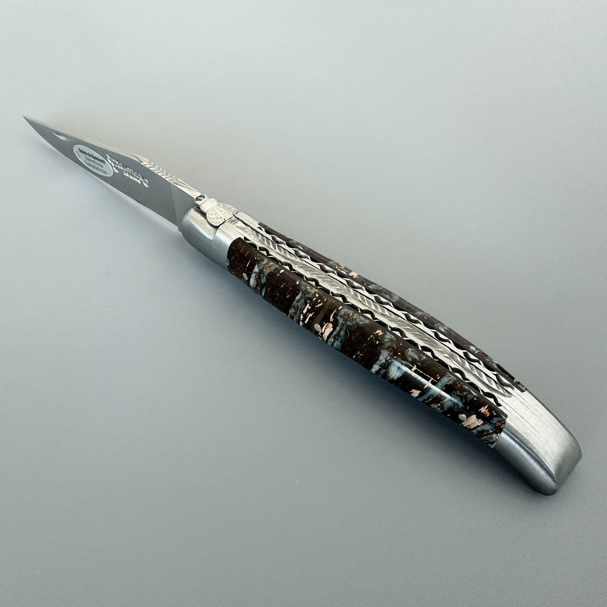 Angled view of a Laguiole en Aubrac double-plated knife with brown mammoth molar handle and decorated file work