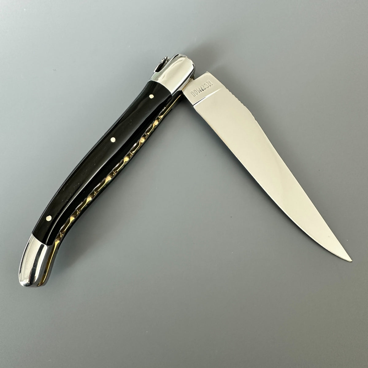 Reverse side of Laguiole en Aubrac double-plated pocket knife with a buffalo horn handle and brass inner spine