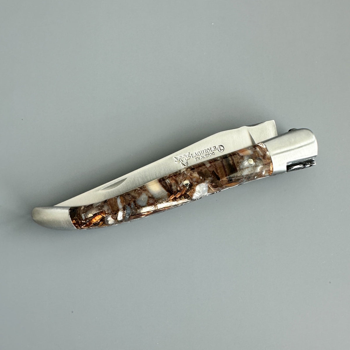 Reverse side of Laguiole en Aubrac Folding Knife with Fusion Mammoth Ivory handle handle fully closed over gray background