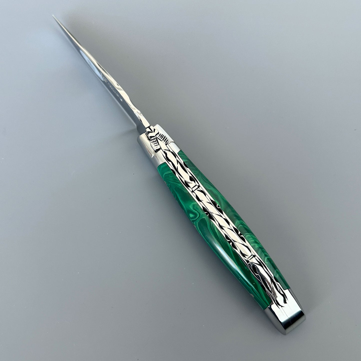 Angled Laguiole en Aubrac malachite knife showing hand-decorated file work and polished bolsters