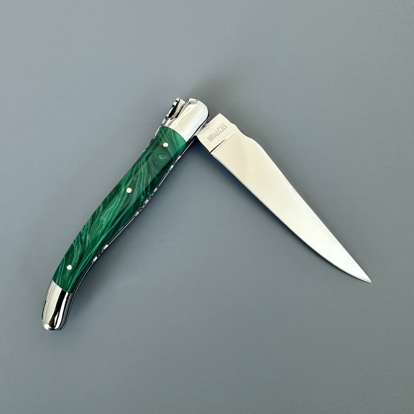 Reverse view of an open Laguiole en Aubrac double-plated knife with green malachite handle