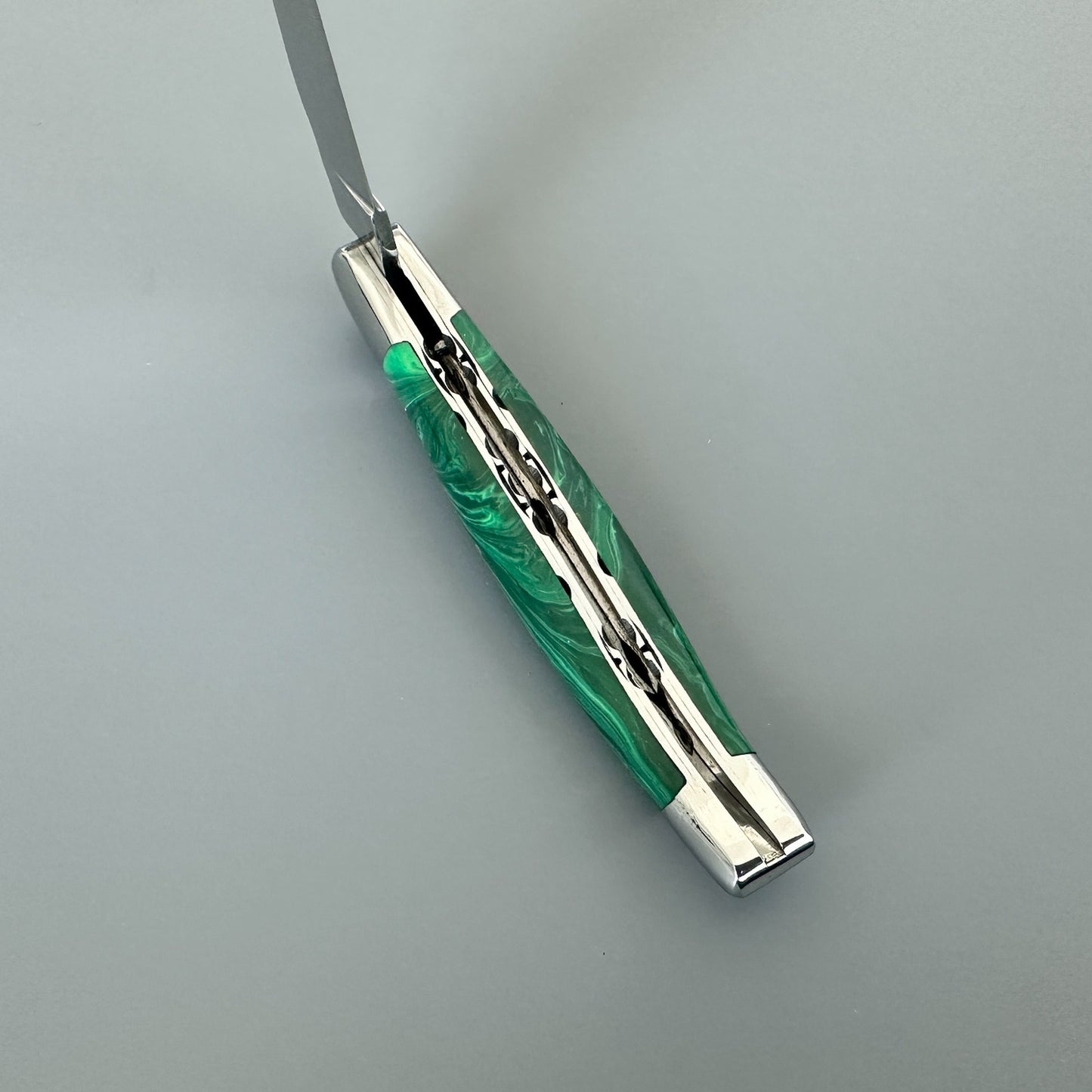 Angled spine view of a Laguiole en Aubrac double-plated knife with green malachite handle and file work