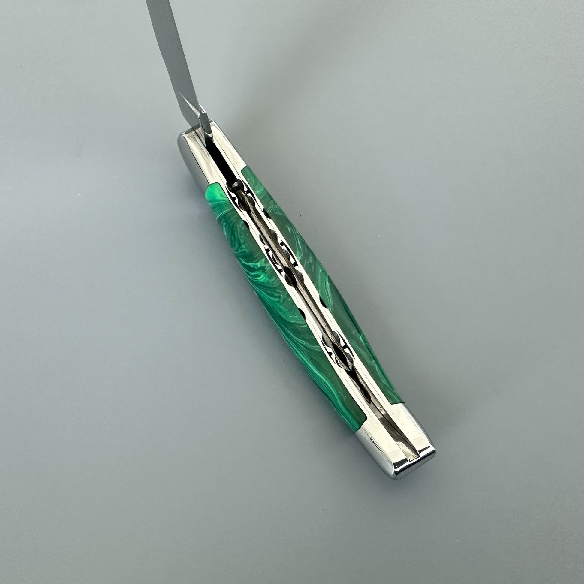 Angled spine view of a Laguiole en Aubrac double-plated knife with green malachite handle and file work