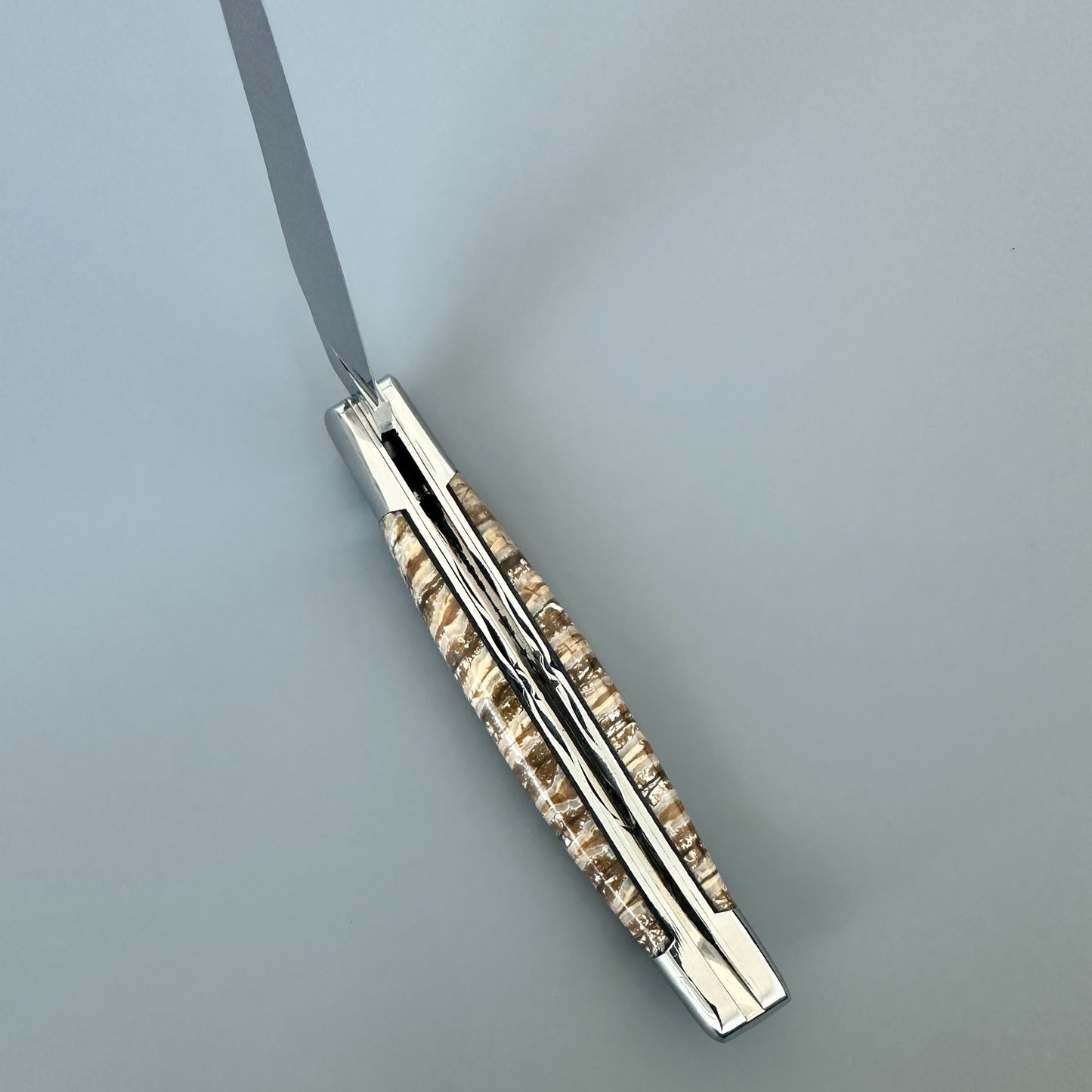 Angled view of a Laguiole en Aubrac knife showing decorated file work and mammoth molar scales