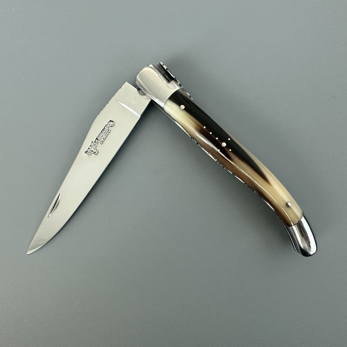 Partially open Laguiole en Aubrac double plated pocket knife with solid horn flame handle