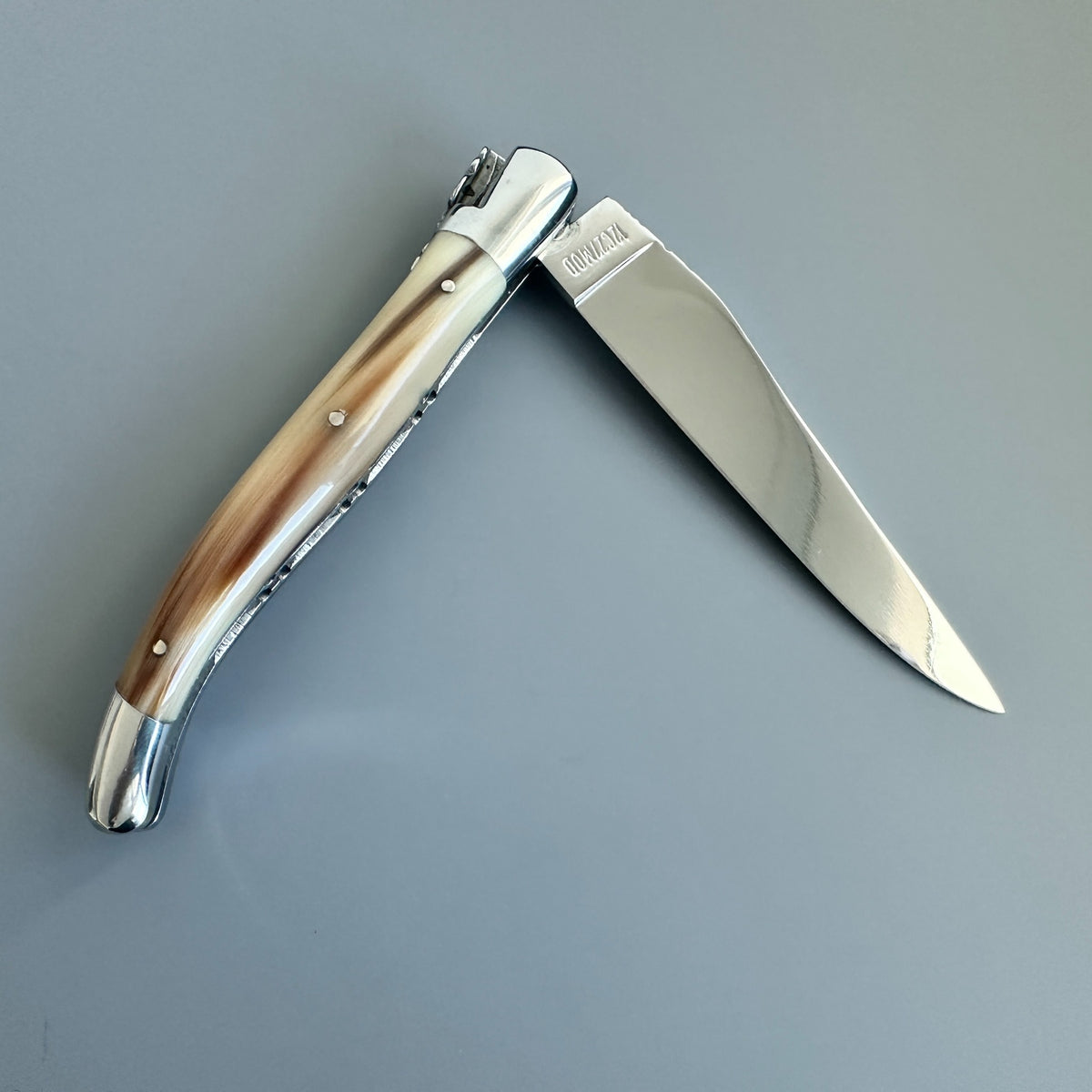 Reverse side of Laguiole en Aubrac double plated pocket knife with solid horn flame handle