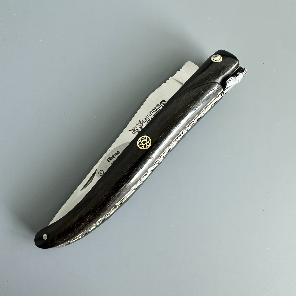 Laguiole en Aubrac folding knife in closed position with Ebony handle and brass mosaic pin.