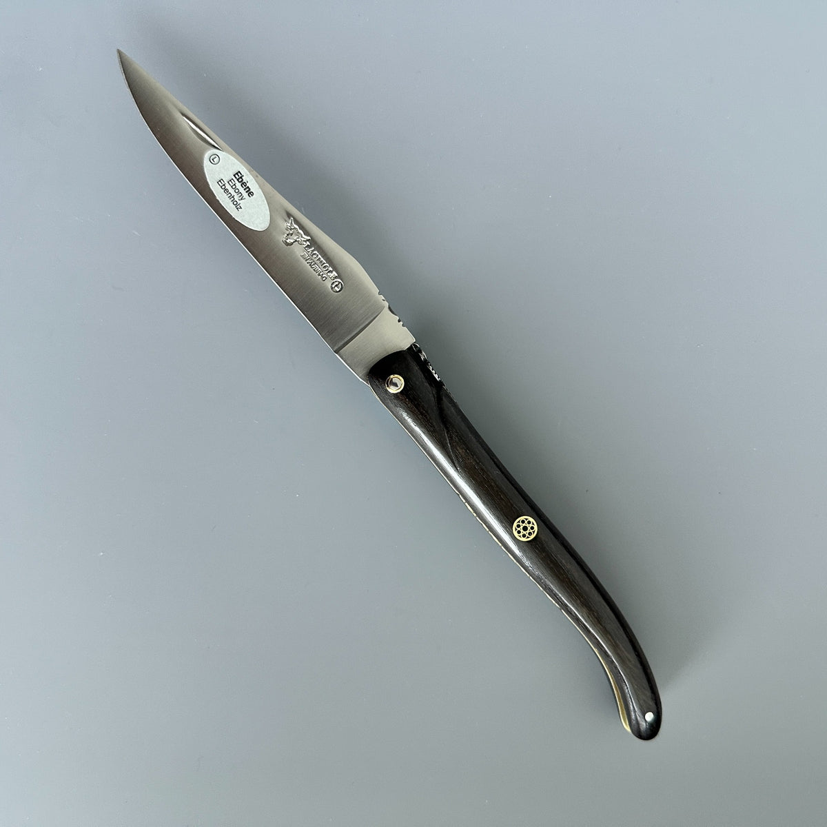 Laguiole en Aubrac folding knife with a satin-finished silver steel blade shown diagonally on a neutral gray background. 