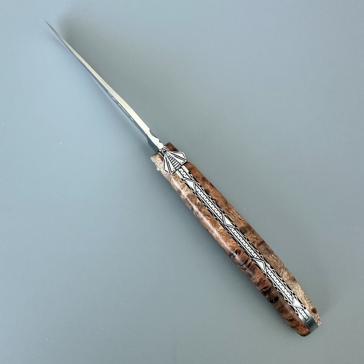 Laguiole en Aubrac Belle Piece with a long, slender silver blade and a decorative handle made of Albizia burl
