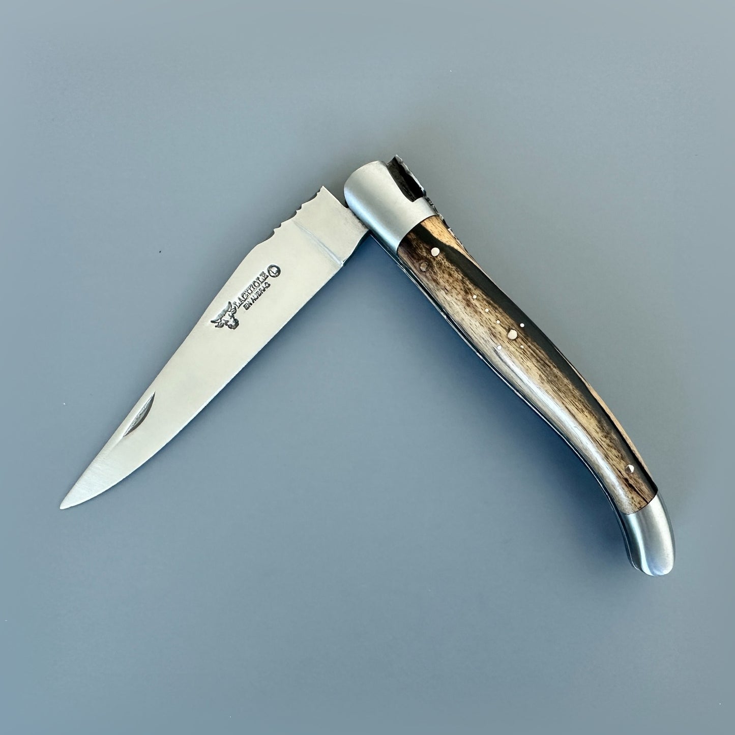 Partially closed Laguiole en Aubrac hand-carved folding knife highlighting its two-tone Royal Ebony handle and satin-finished bolsters.