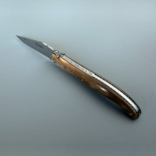 Laguiole en Aubrac mammoth ivory folding knife open at an angle, showing the engraved bee and decorated spring