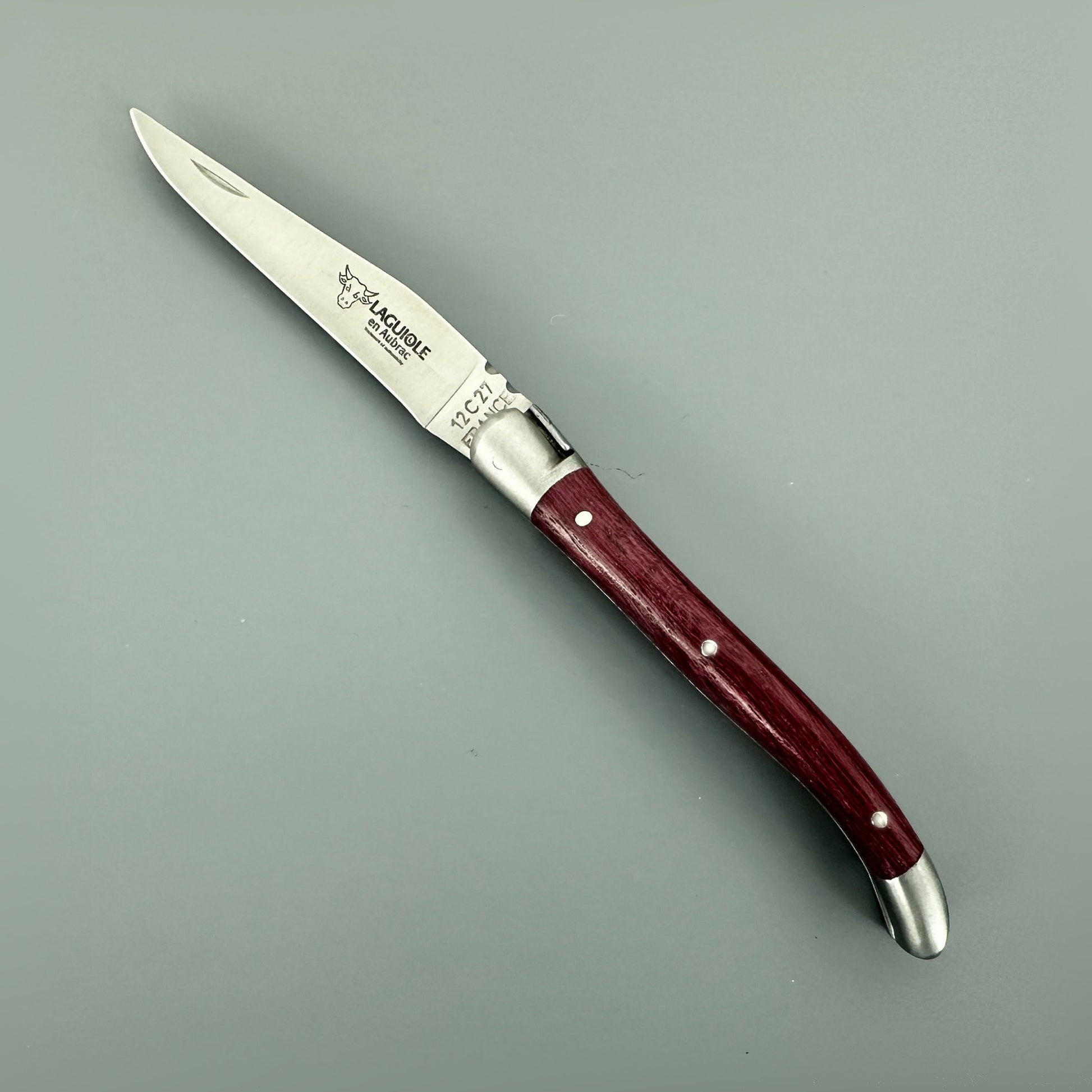 Side view of the open Laguiole en Aubrac Mini Folding Knife with a deep reddish-purple Amaranth handle.