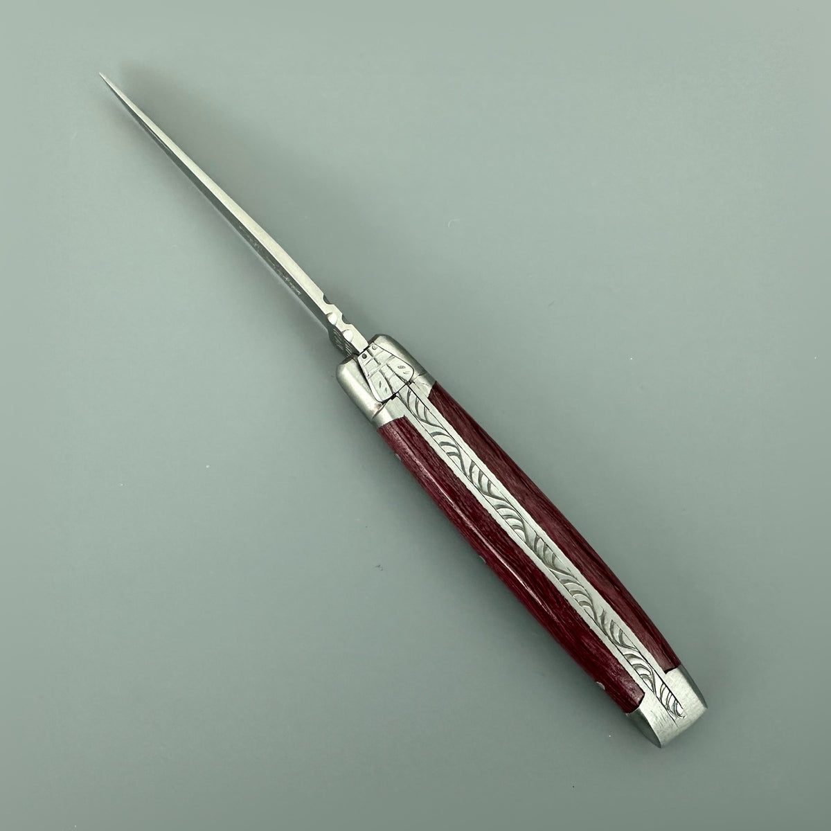 Open Laguiole en Aubrac Mini Folding Knife showing its decorated spine and Amaranth wood handle.