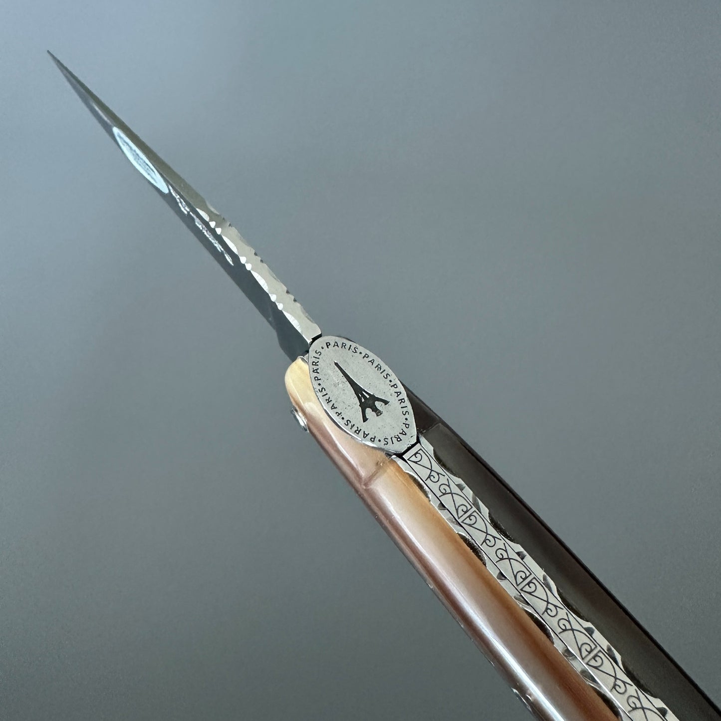 Close-up of the Eiffel Tower medallion and decorated spine on a Laguiole en Aubrac Origine knife