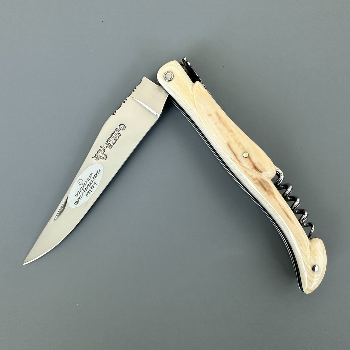 Partially open Laguiole en Aubrac folding knife with a pale patterned handle, corkscrew, and blade logo.