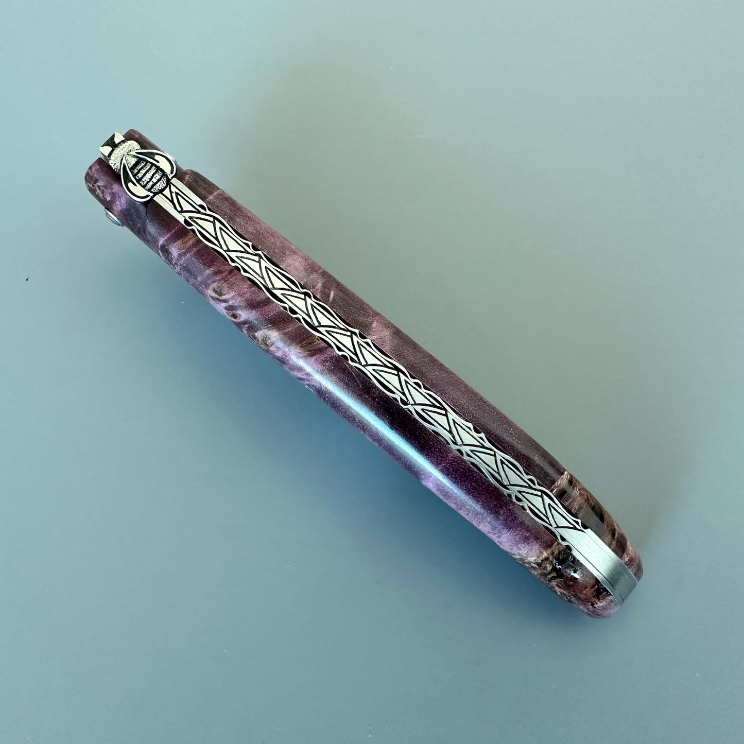 Closed Laguiole en Aubrac L0512WPH/FS-BP55 highlighting the decorated spine and Purple Poplar Burl handle.