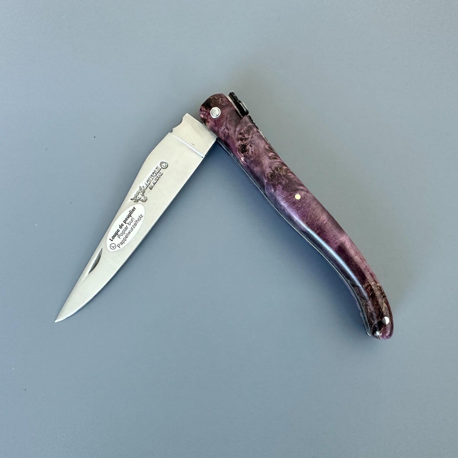 Partially closed Laguiole en Aubrac L0512WPH/FS-BP55 knife displaying its Purple Poplar Burl handle and blade engraving.